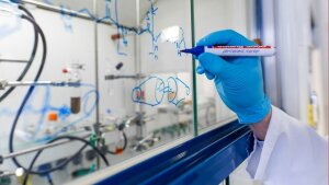 Chemical formula are being written on the window of the fume hood.